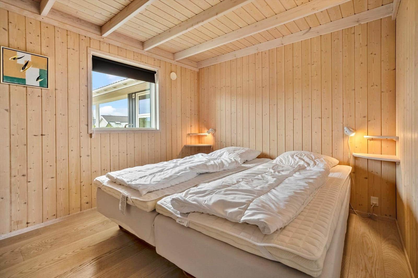 Bedroom with wooden walls, double bed, and window with view.