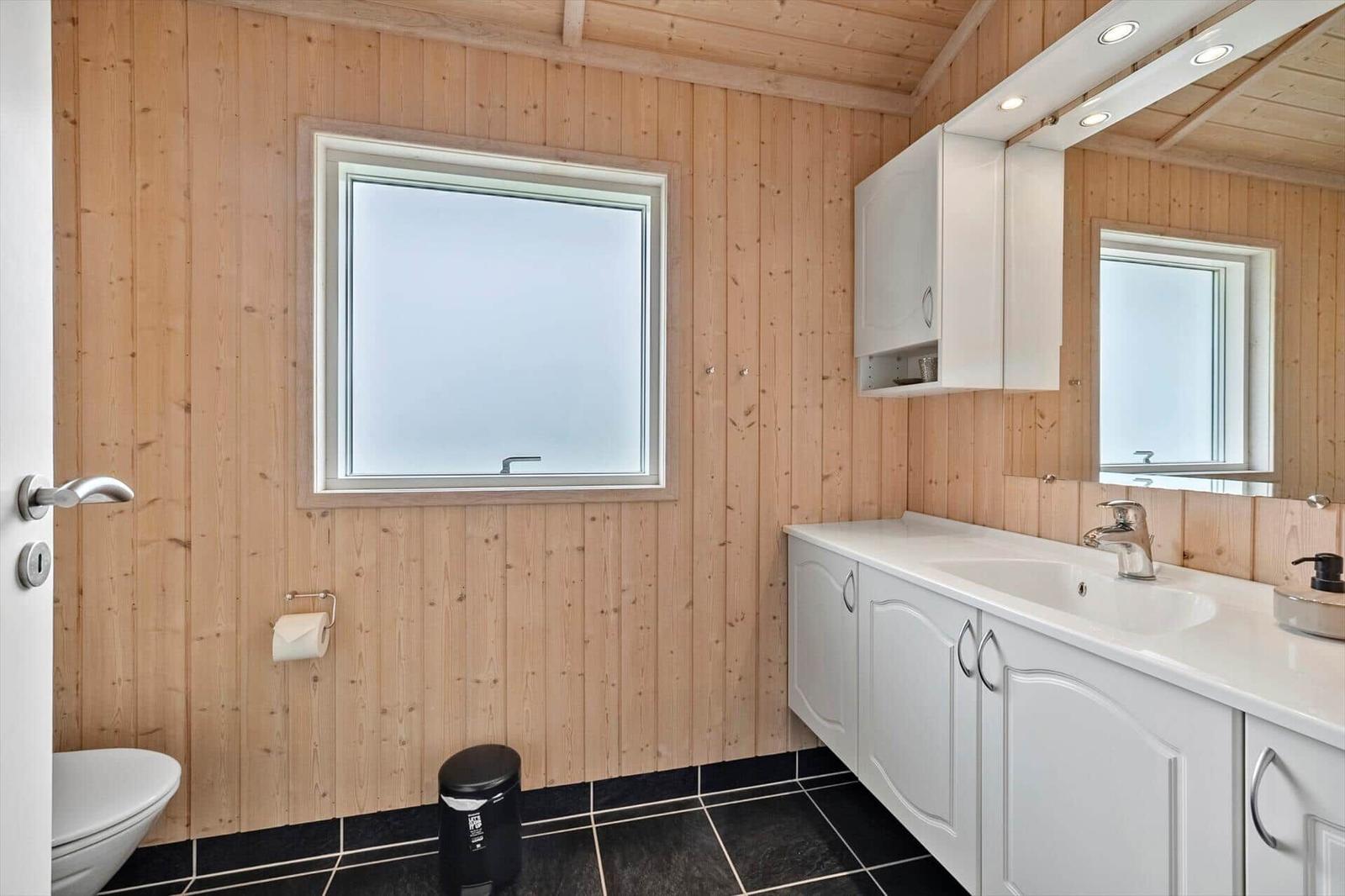 Bathroom with wooden walls, sink, and window