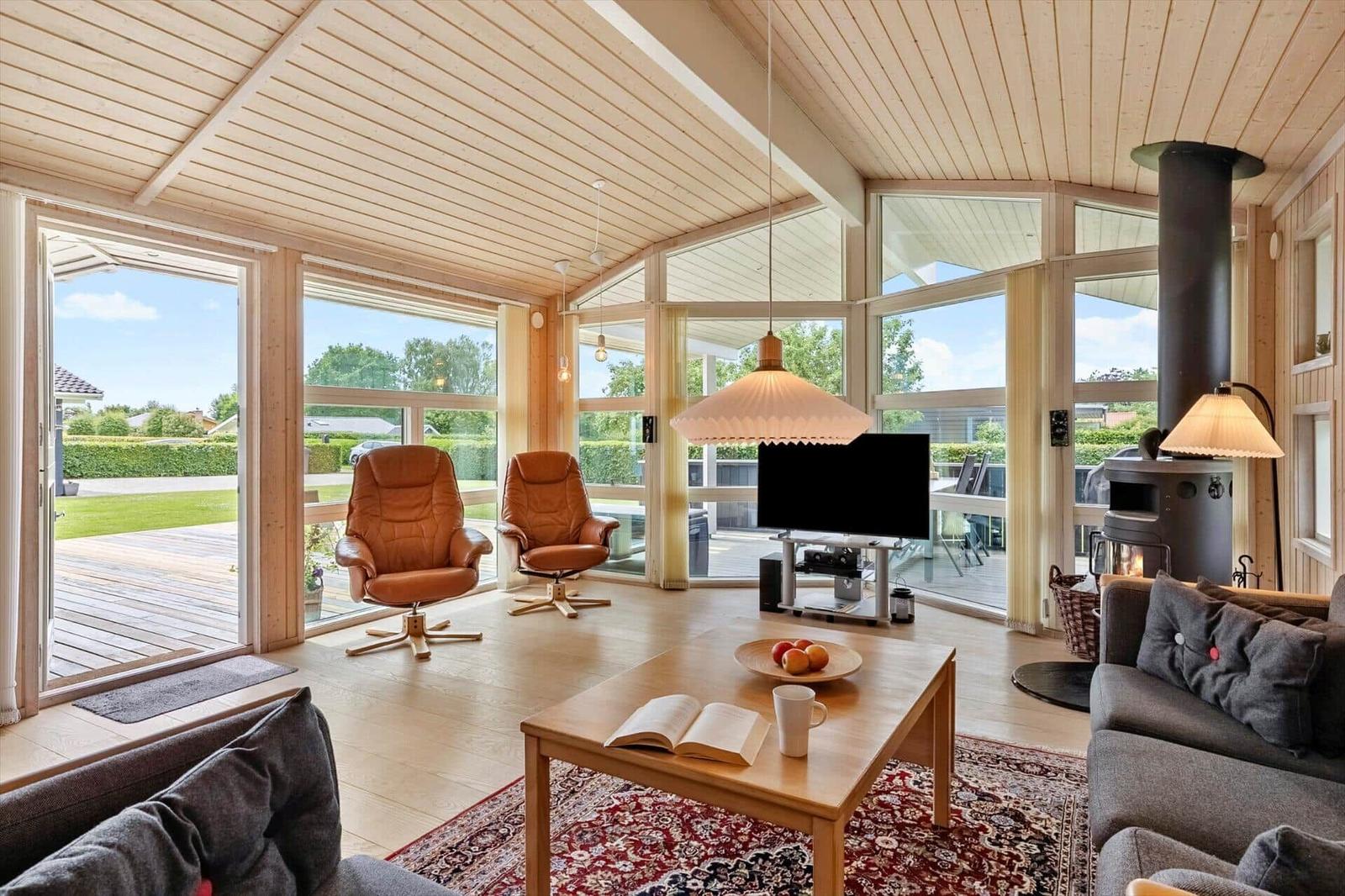 Living room with wooden ceiling, seating, and view of the terrace.