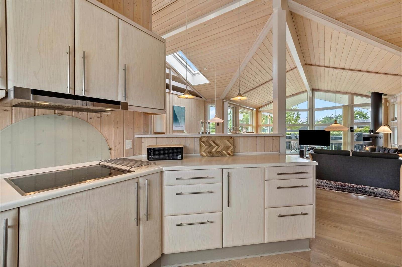 Modern kitchen with wooden elements and view into living area.