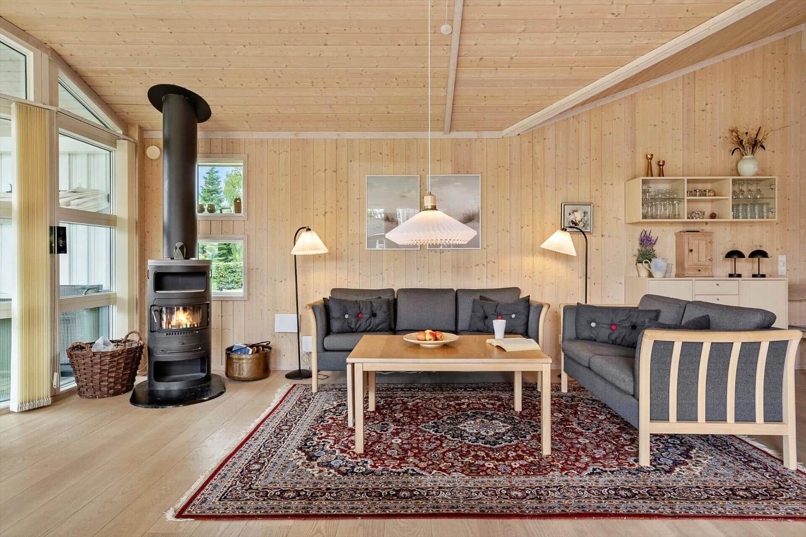 Living room with wood walls, fireplace, sofa, and rug.