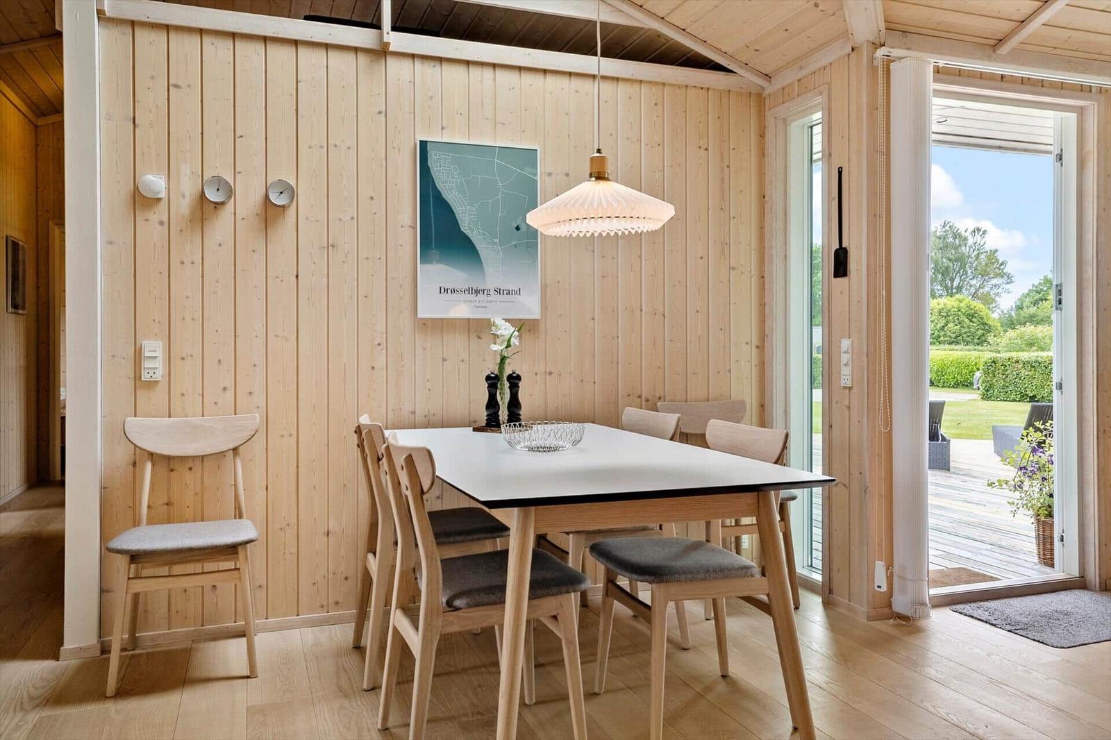 Dining room with wooden walls, table and chairs, view of the garden.