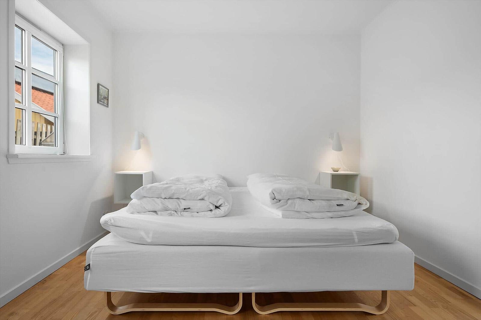 Ein Schlafzimmer mit einem Bett, zwei Nachttischen und einem Fenster.