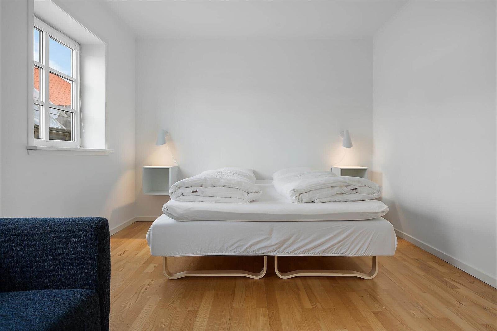 Schlafzimmer mit Bett, Fenster und Holzboden.