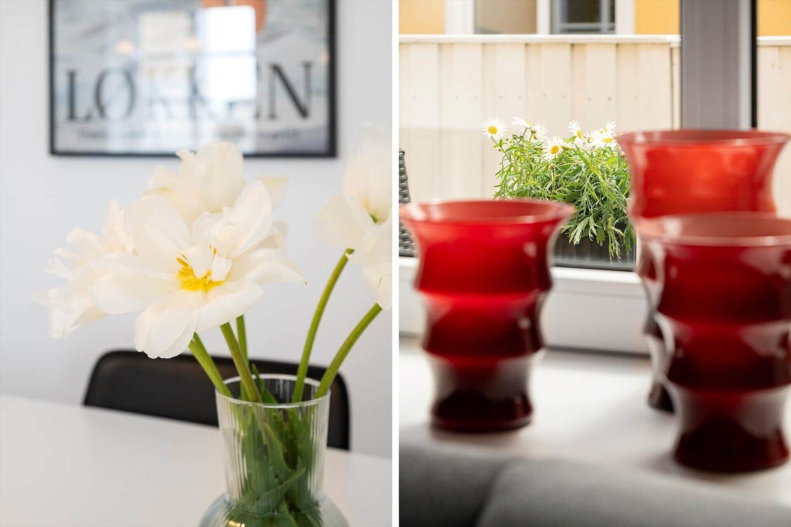 Weiße Blumen in einem Glas auf Tisch. Rote Gläser und Blumen auf Balkon.