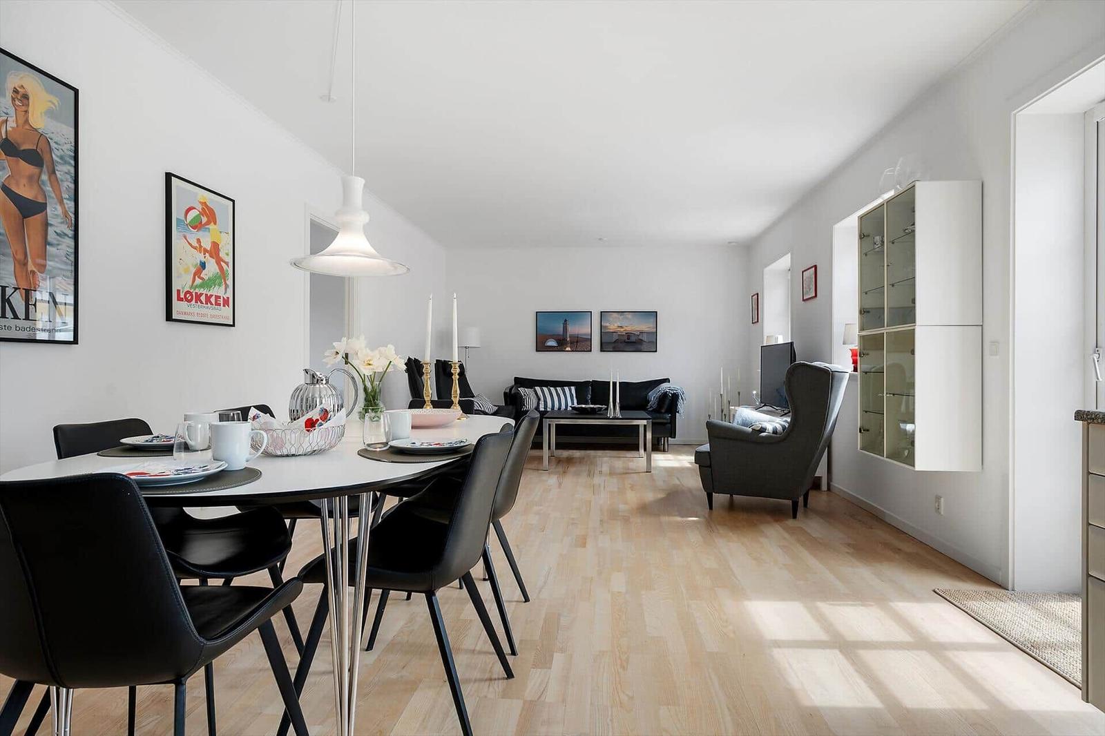 Esszimmer mit Tisch und Stühlen. Wohnbereich mit Sofa, Sessel und Wandbildern.