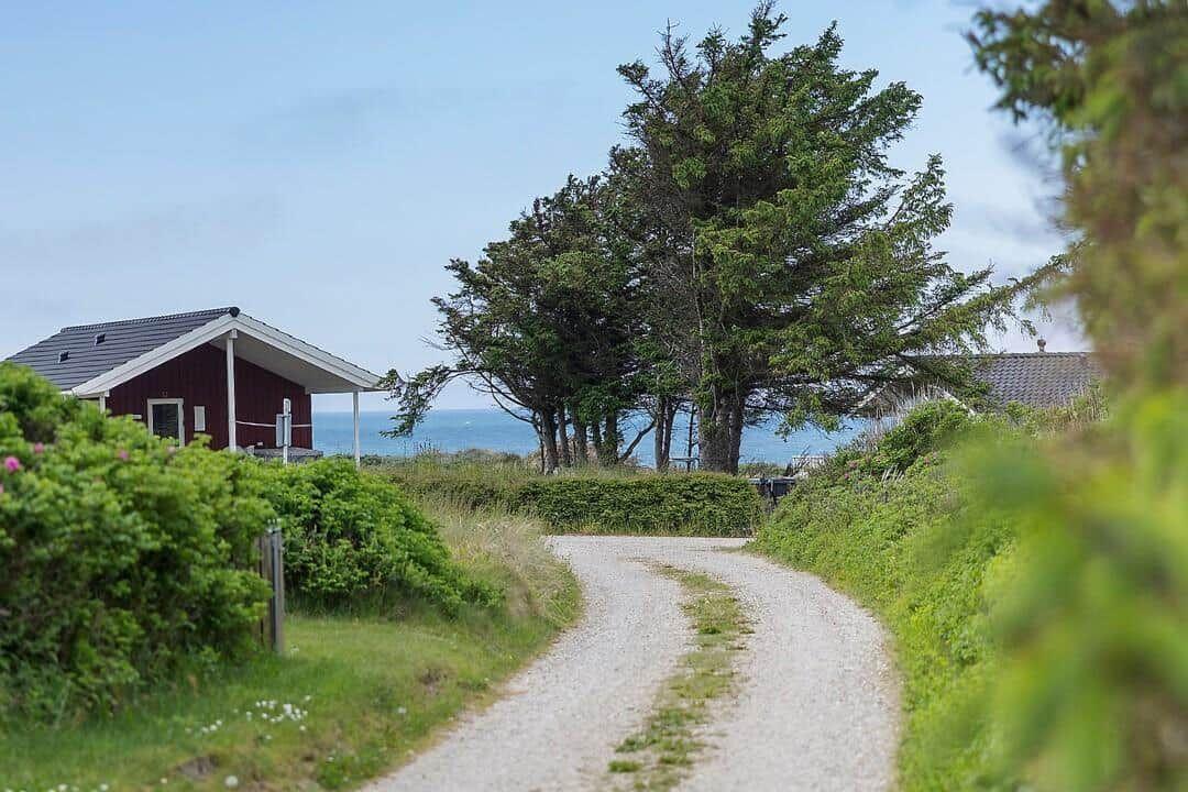 Gehweg führt zu einem roten Haus mit Blick aufs Meer.
