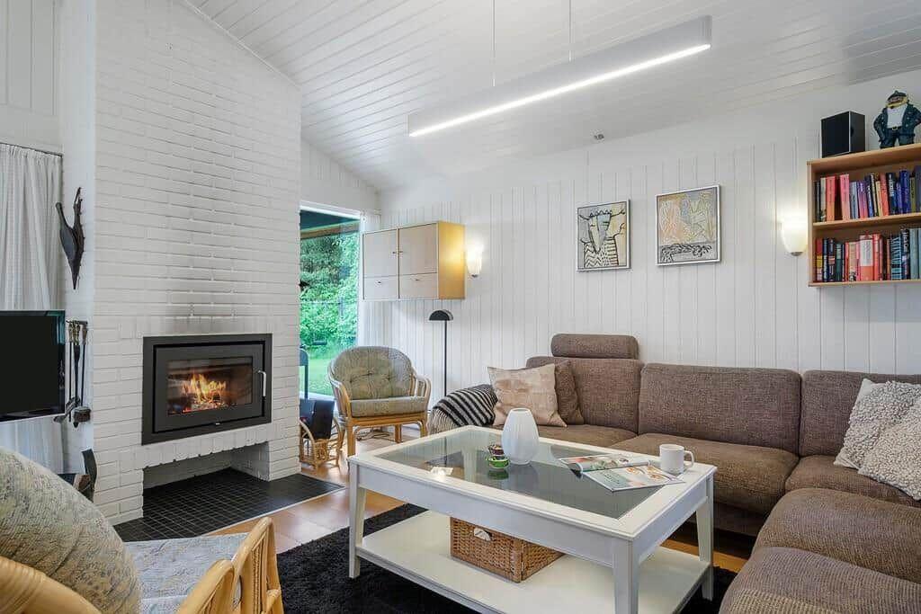 Living room with sofa, fireplace, and glass-top table. Bookshelf and wall art visible.