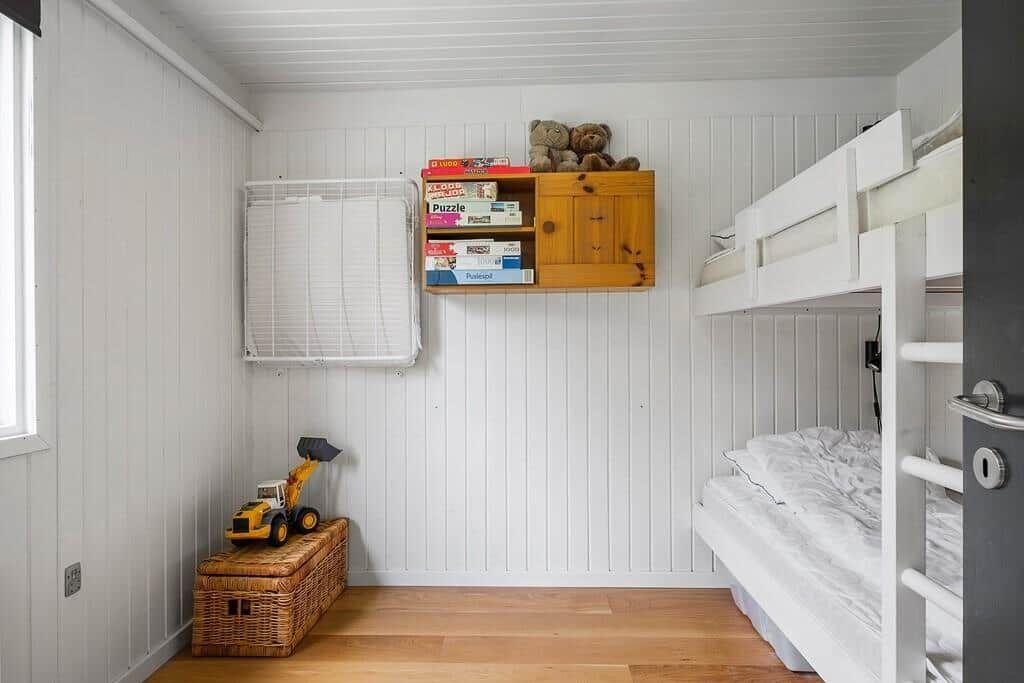 Childrens room with bunk bed, wooden shelf, and toys.