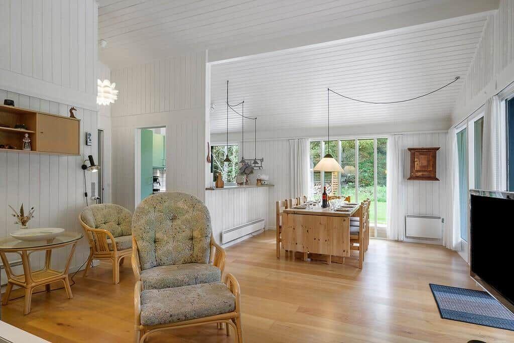 Living and dining area with hardwood floor, seating, and garden view.
