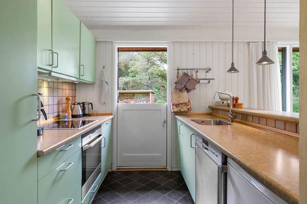 Kitchen with green cabinets, countertops, and view of the garden.