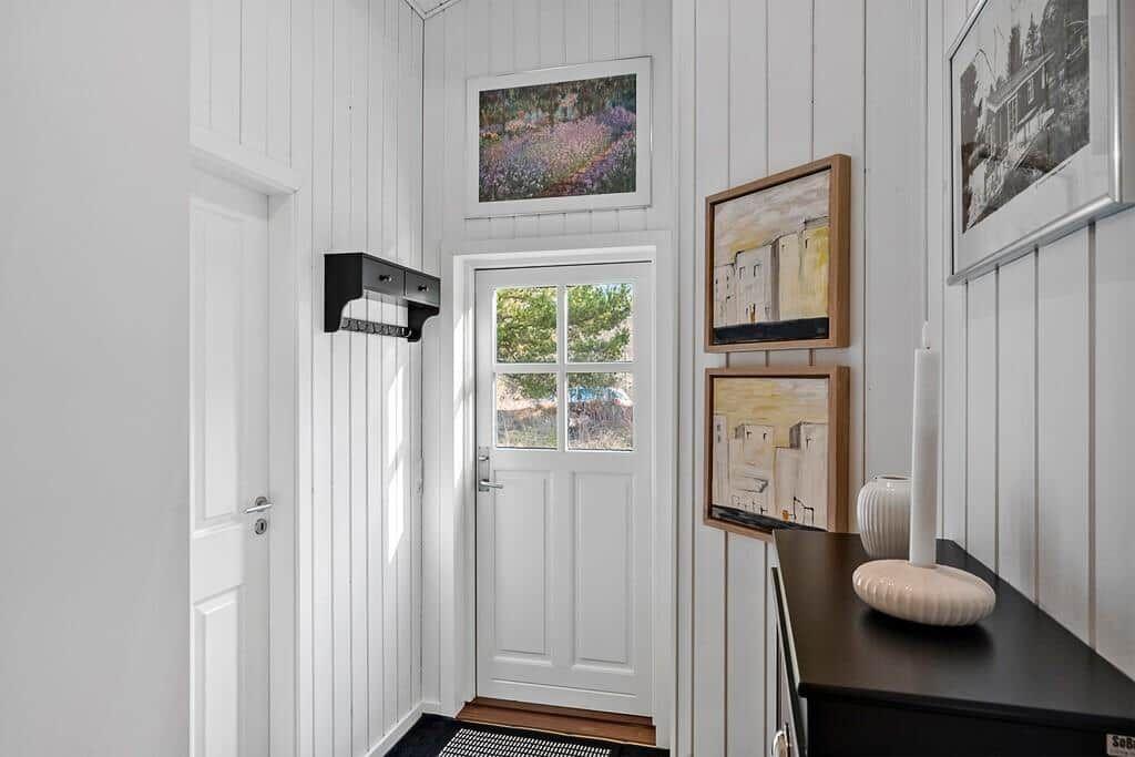Haus-Eingang mit weißen Wänden, Tür und Bildern an der Wand.