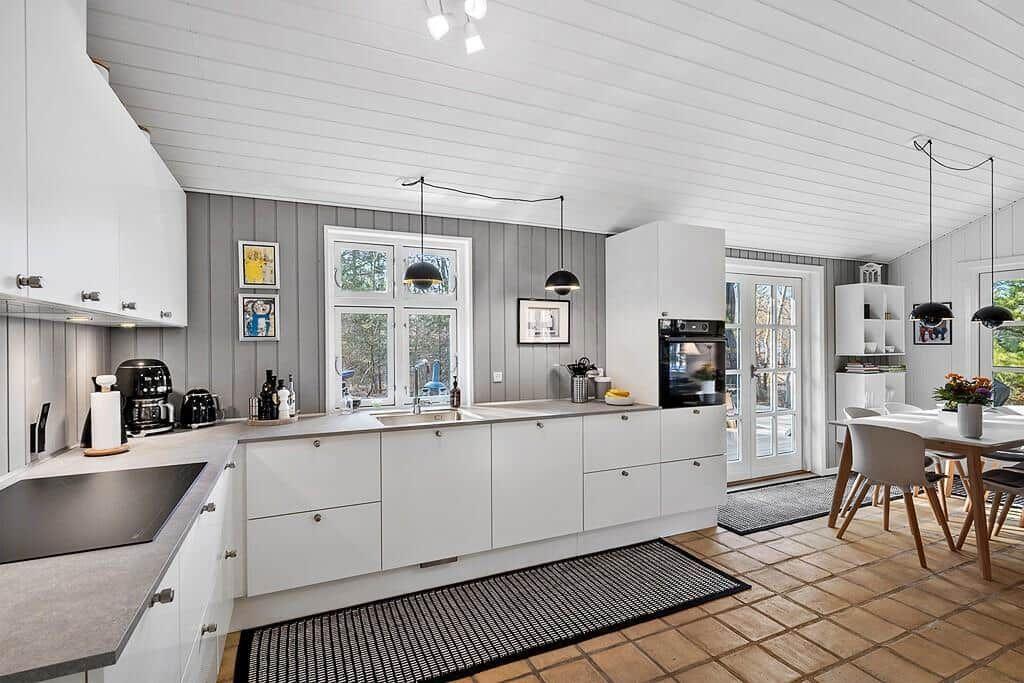 Moderne Küche mit weißen Schränken, Arbeitsplatte und Fenster. Essbereich mit Tisch und Stühlen.