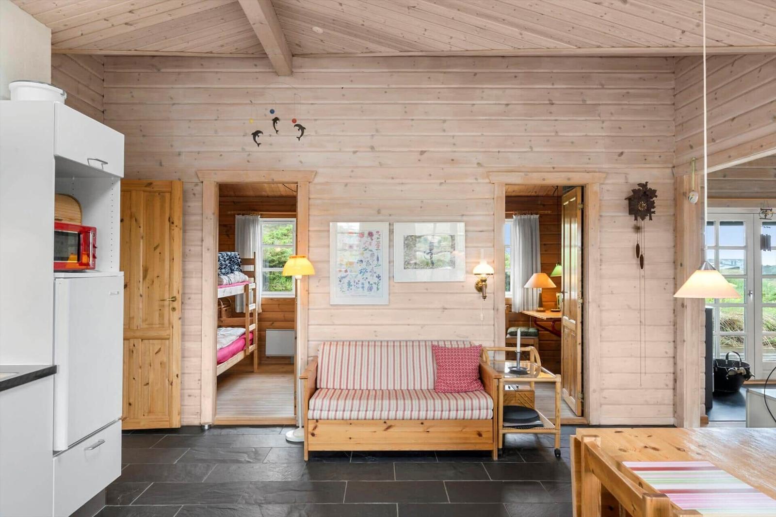 Wohnbereich mit Sofa, Küchenzeile und Blick in Schlafzimmer und Essbereich.