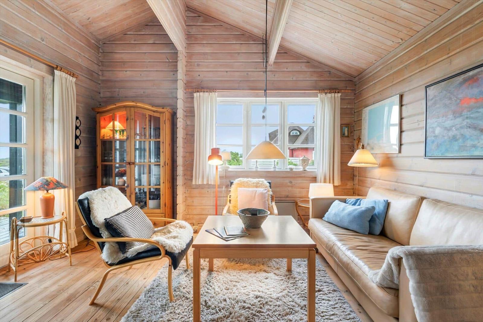 Wohnzimmer mit Holzwand, Sofa, Sessel und Tisch