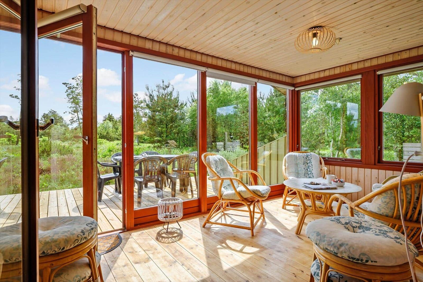 Terrasse mit Sitzgruppe und Blick auf Garten. Holzdecke und Fensterfront.