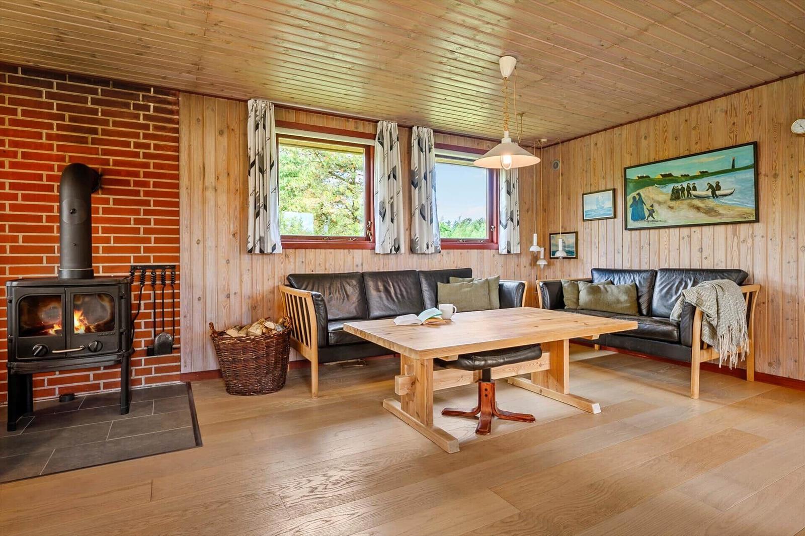 Wohnzimmer mit Holzfußboden, Sofa, Tisch und Kaminofen an Backsteinwand.