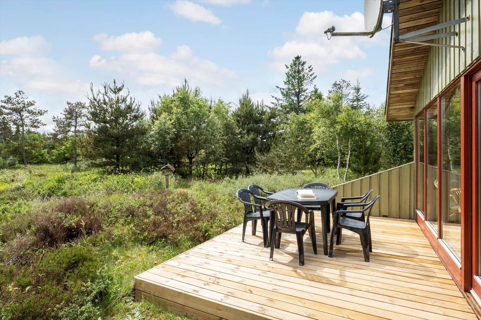 Terrasse mit Tisch und Stühlen, Blick auf Wald und Himmel