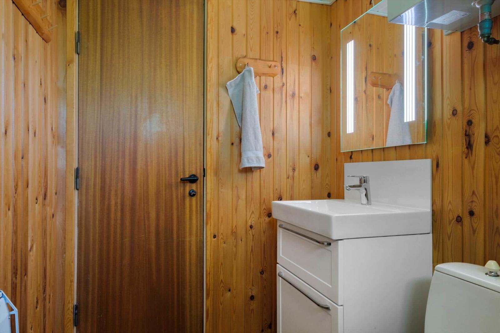 Badezimmer mit Holzwand, Waschbecken und Spiegel