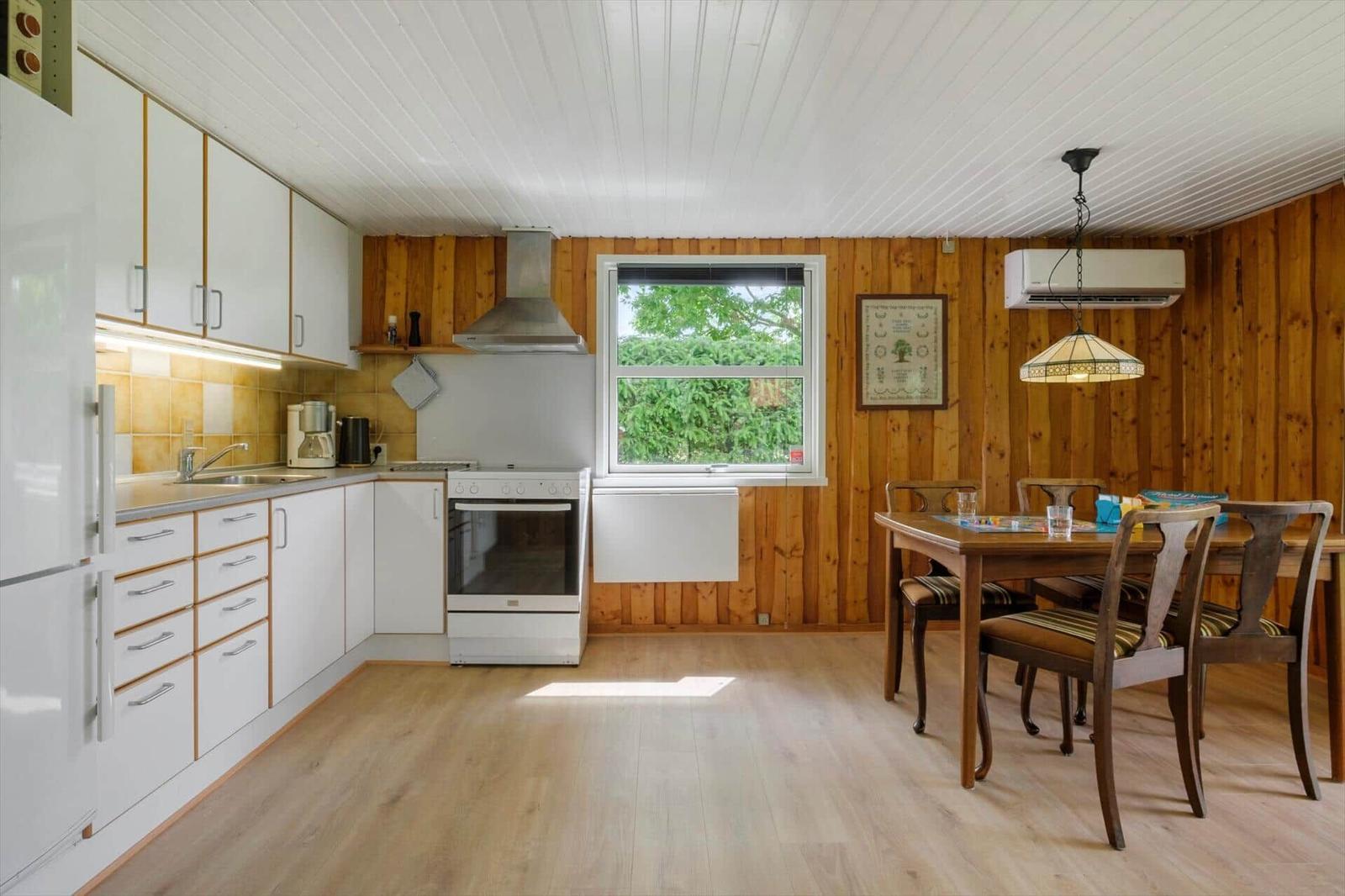Küche mit Essbereich, Holzwand, Fenster und Küchengeräten.