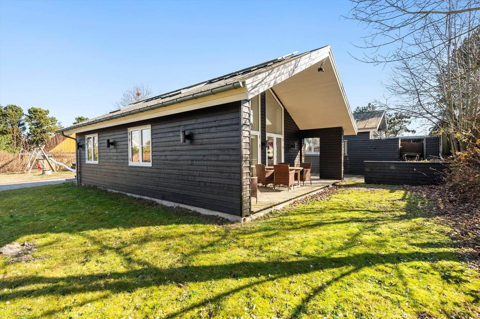 Moderne Holzhütte mit Terrasse und Garten. Außenbereich mit Sitzgelegenheit.