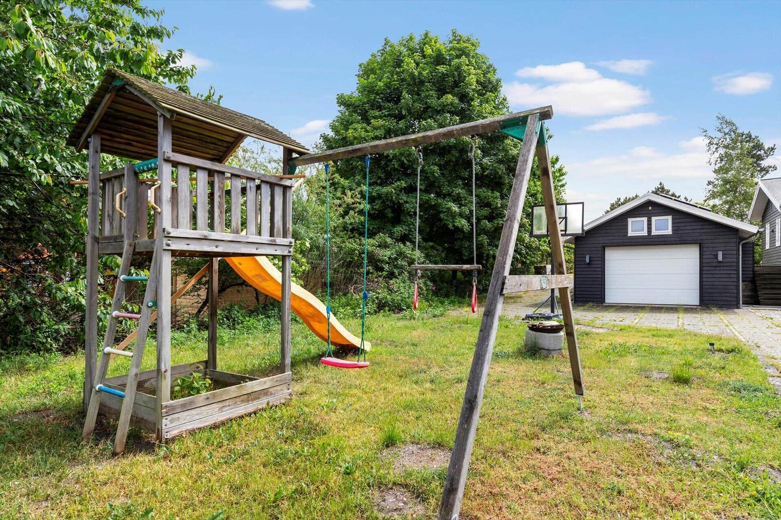 Hinterhof mit Spielplatz, Schaukel und Rutsche. Garage im Hintergrund.