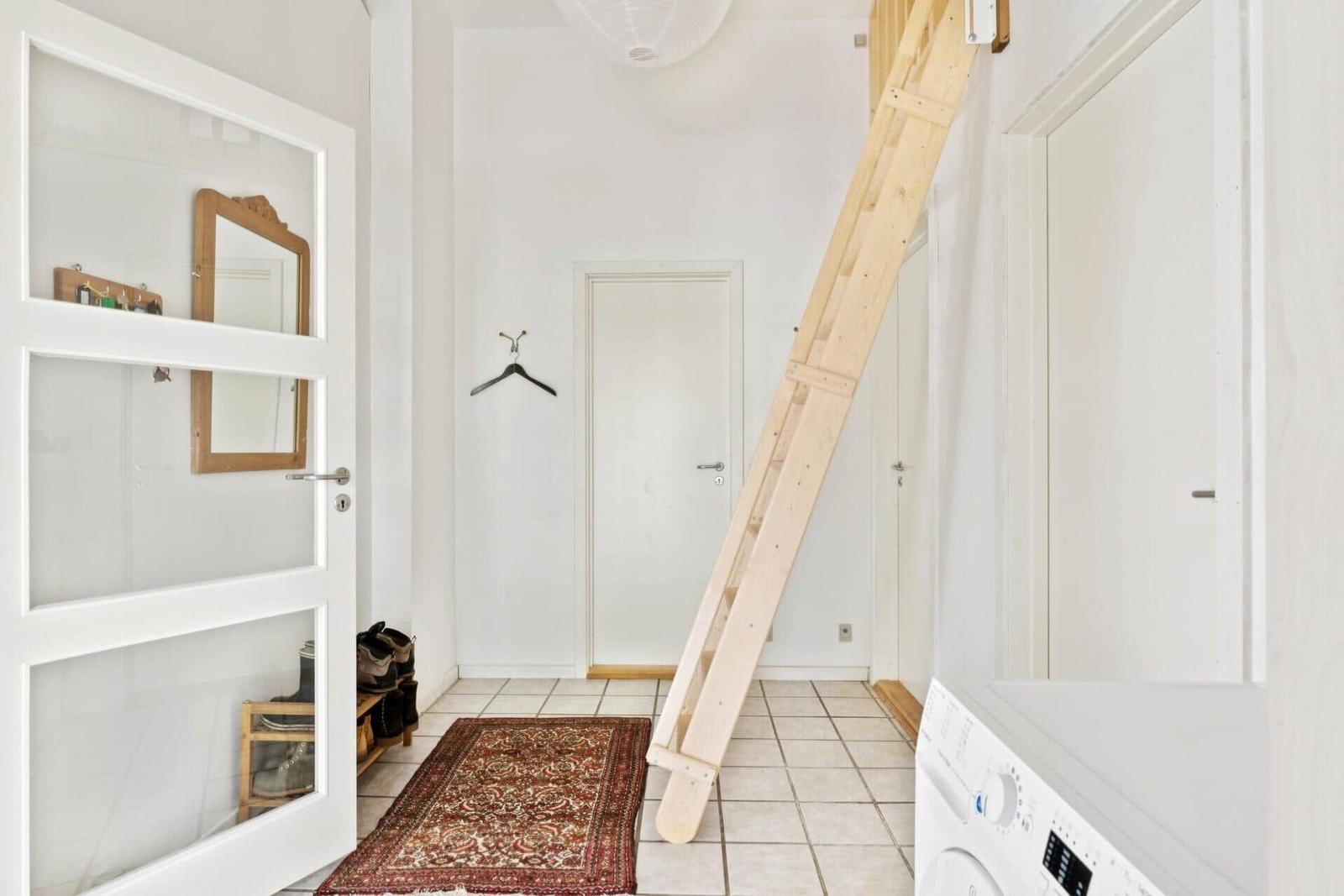 Eingangsbereich mit Holztreppe, Teppich und Waschmaschine