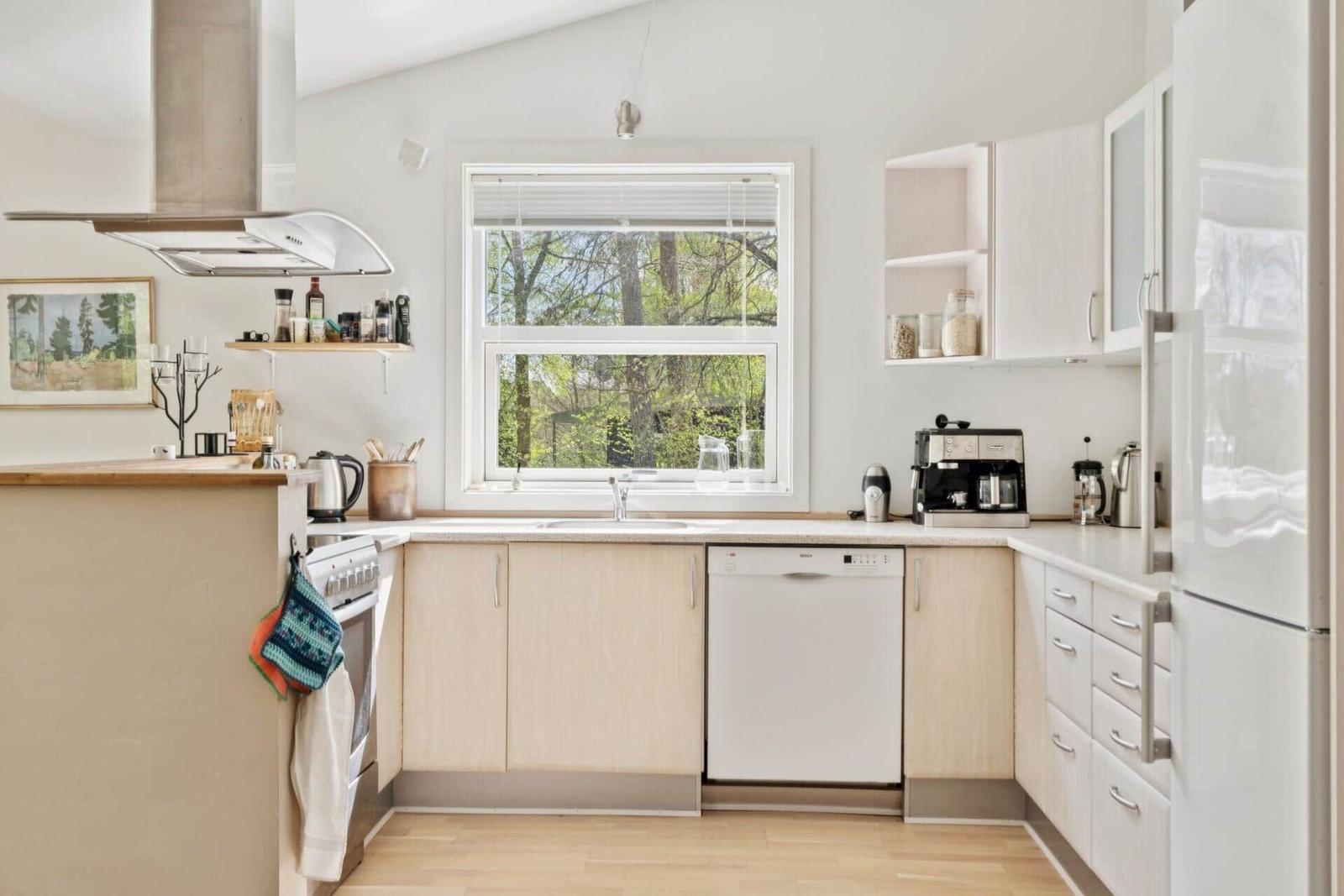 Küche mit Fenster, Spüle, Kühlschrank und Waschmaschine.