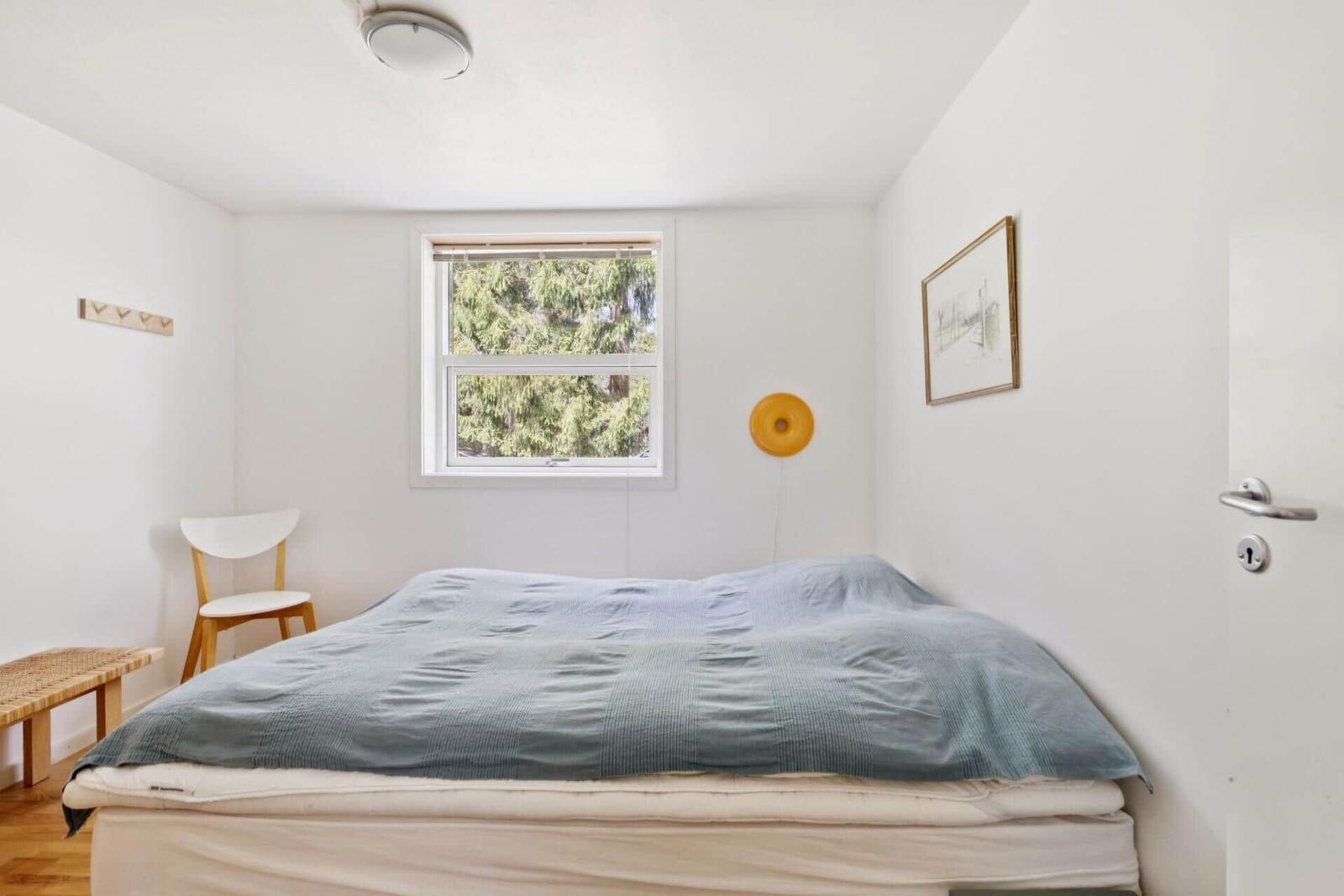 Schlafzimmer mit Bett, Fenster und Stuhl.