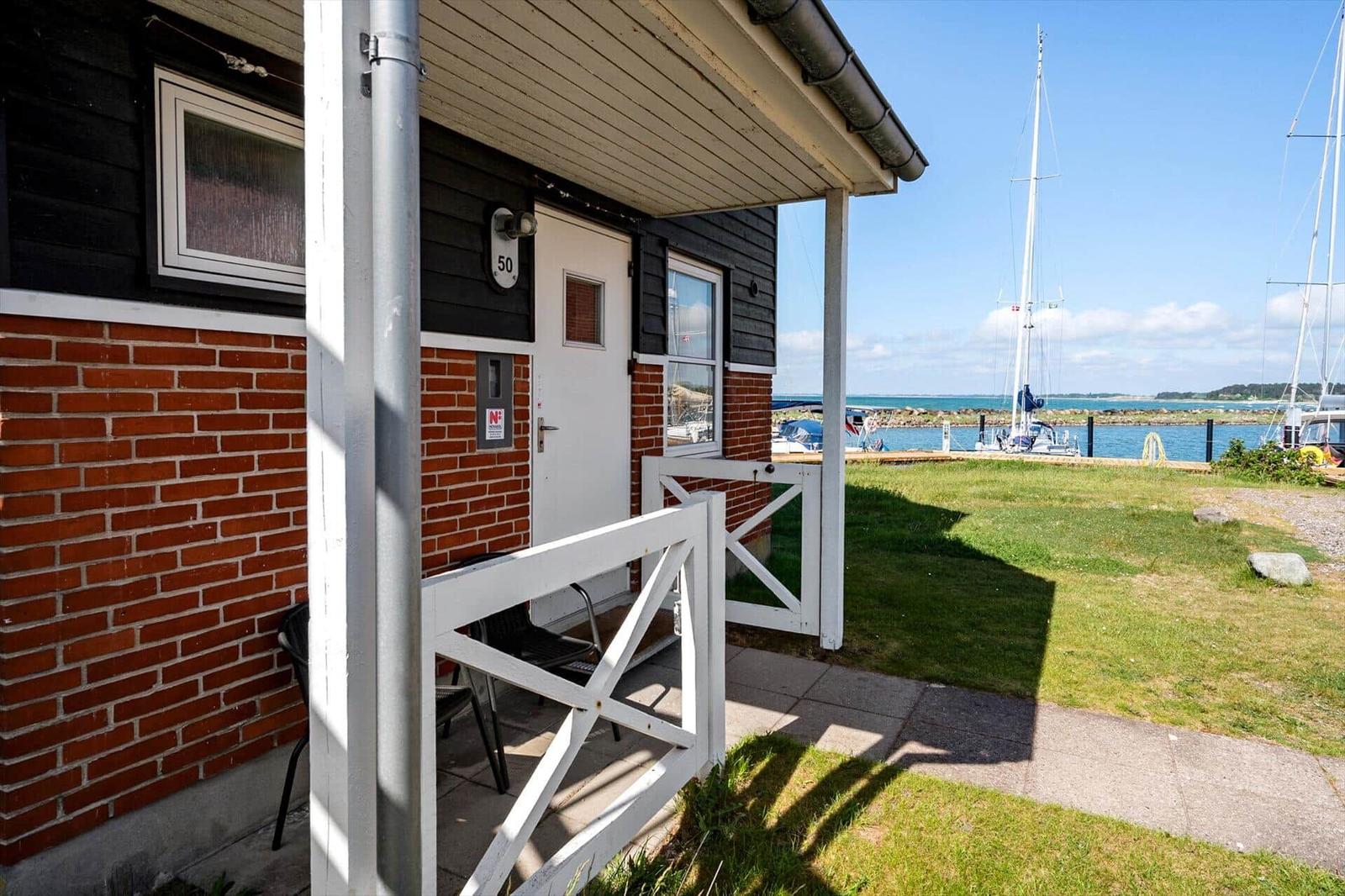 Haus mit weißer Tür und Balkon, Blick auf Hafen mit Segelbooten.