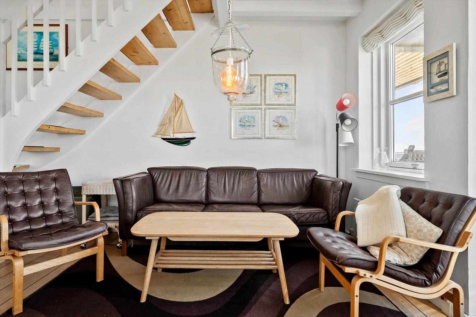 Wohnzimmer mit braunem Ledersofa, Holztisch und Stufen zur Galerie.