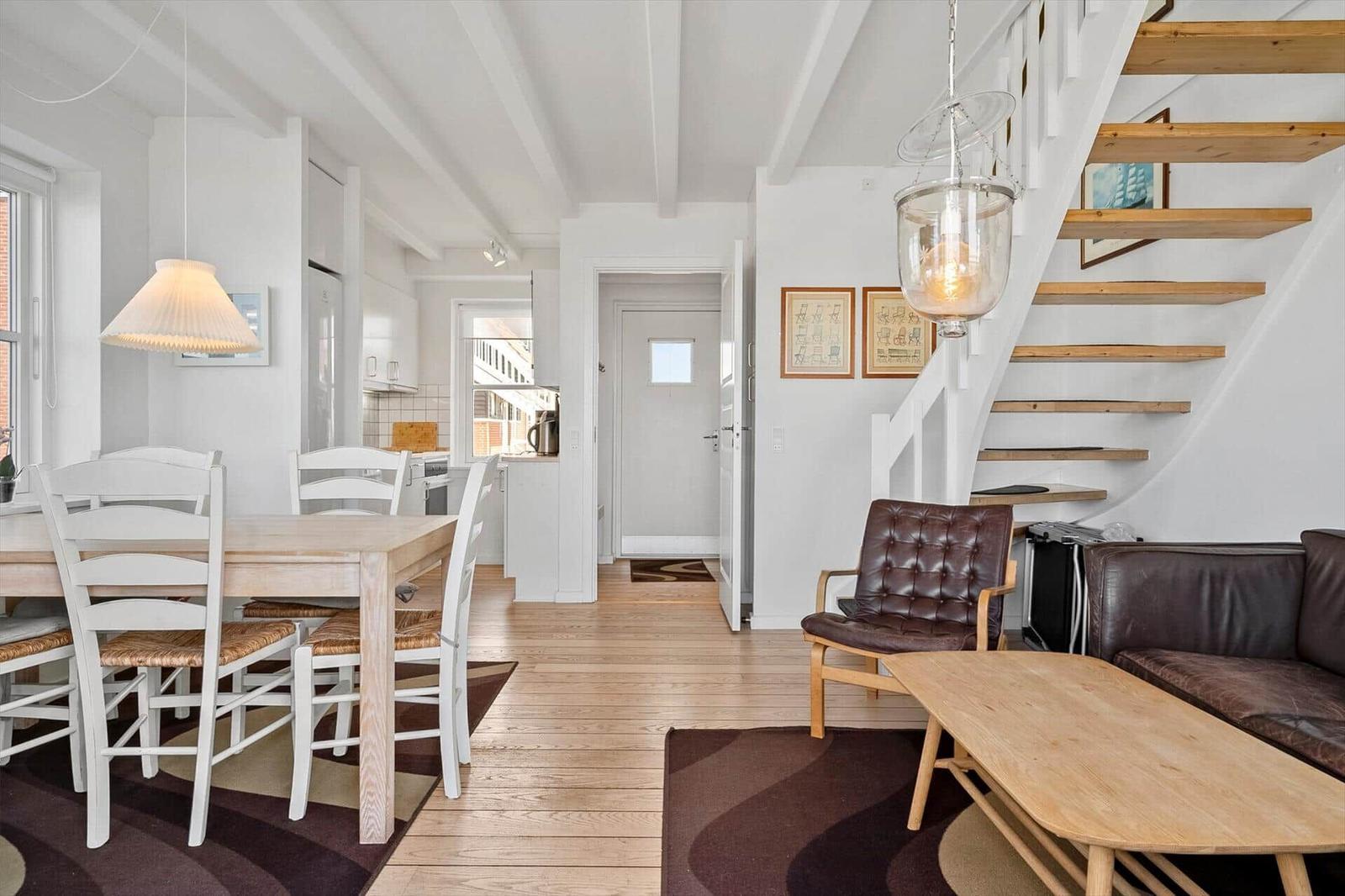 Wohnung mit Essbereich, Holzfußboden und Treppe zur oberen Etage.