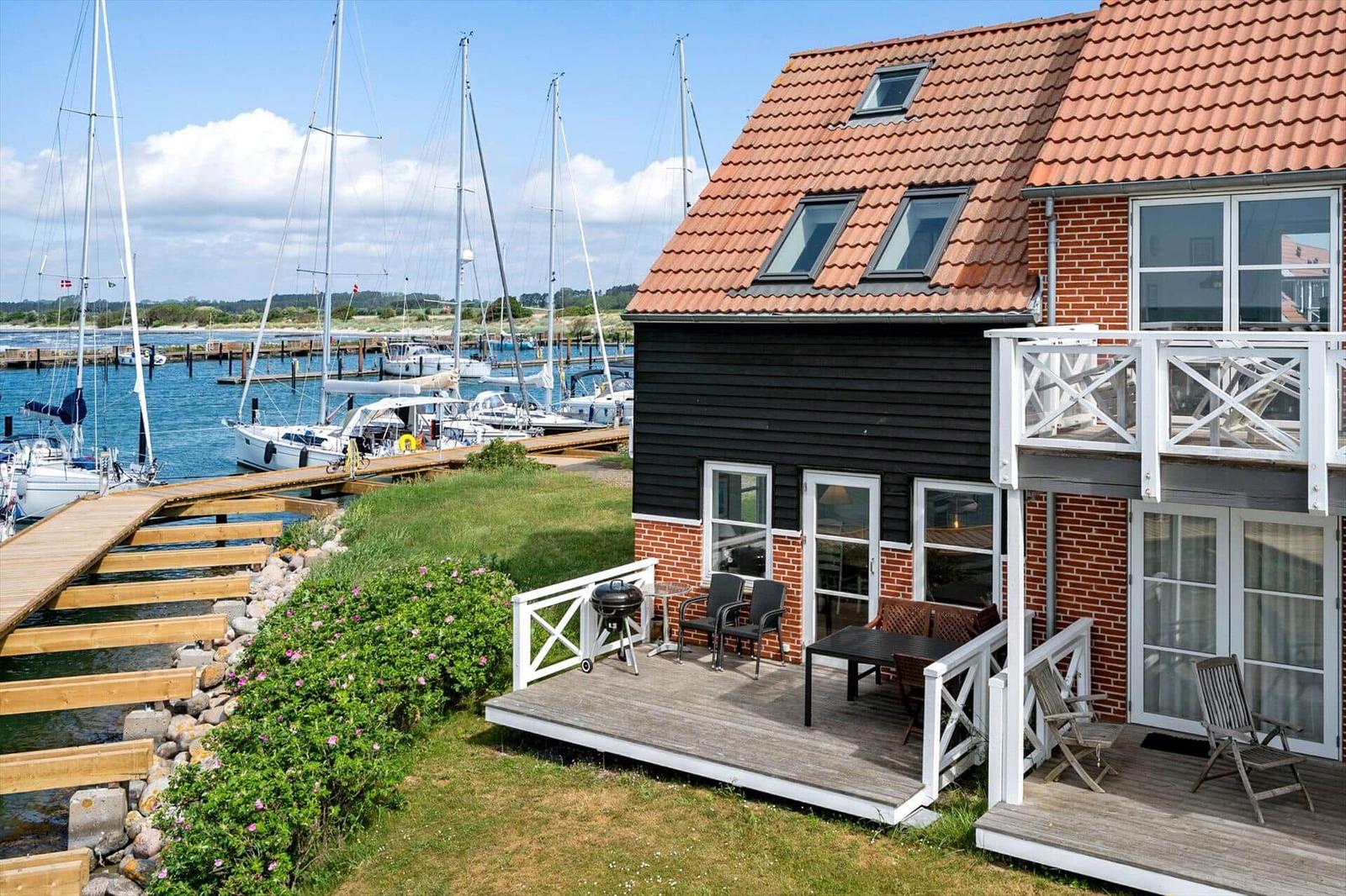 Haus mit Terrasse und Blick auf den Hafen mit Segelyachten.