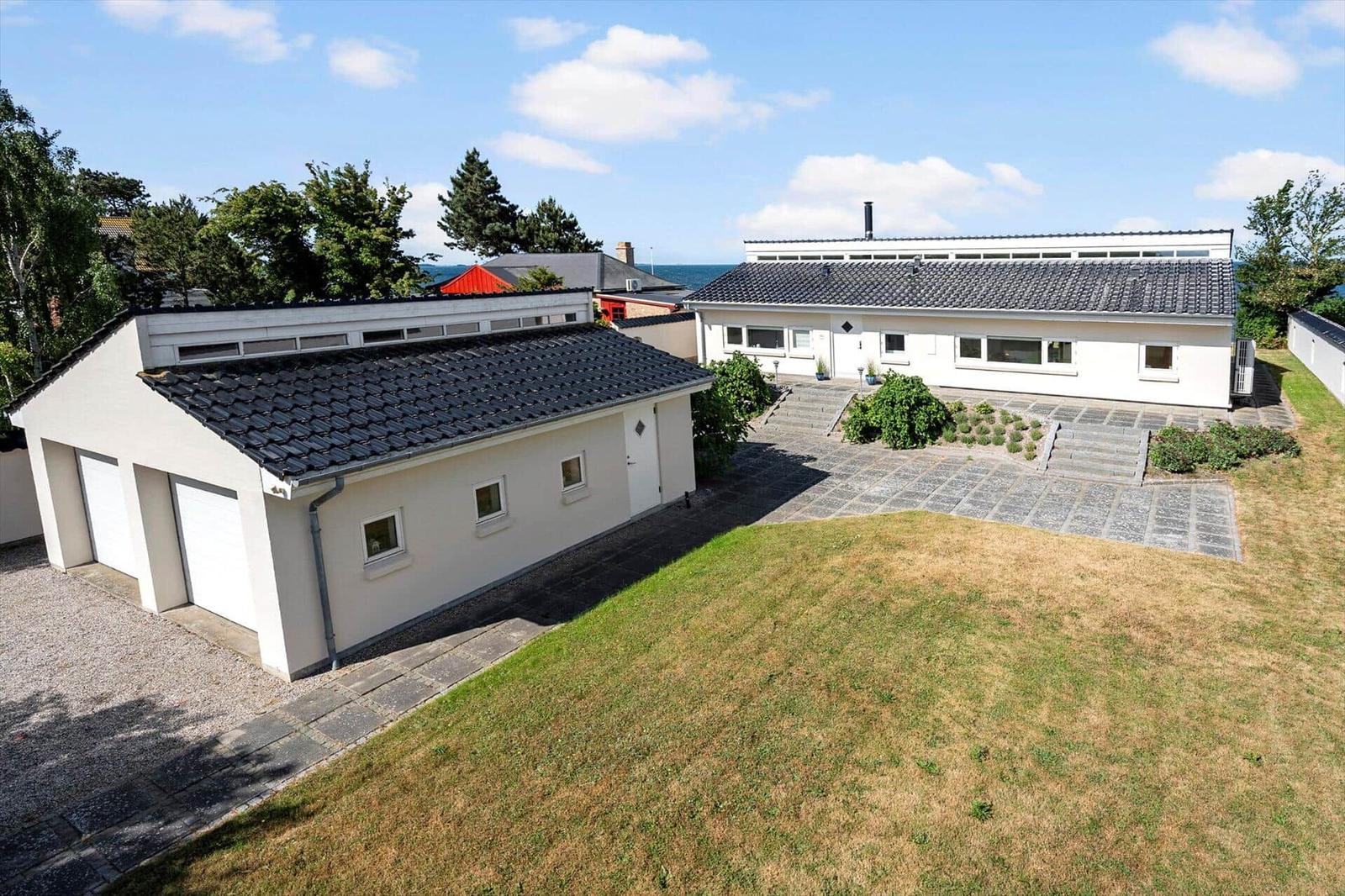 Modern white house with garage and garden. View of the sea.
