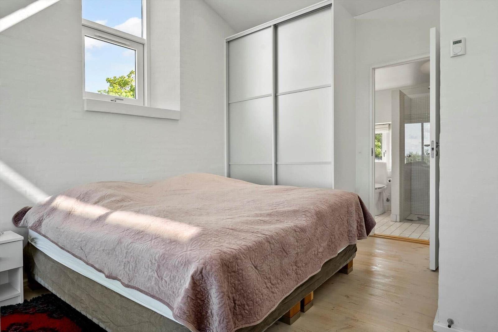 Bedroom with bed, closet, and window. Bathroom is adjacent.