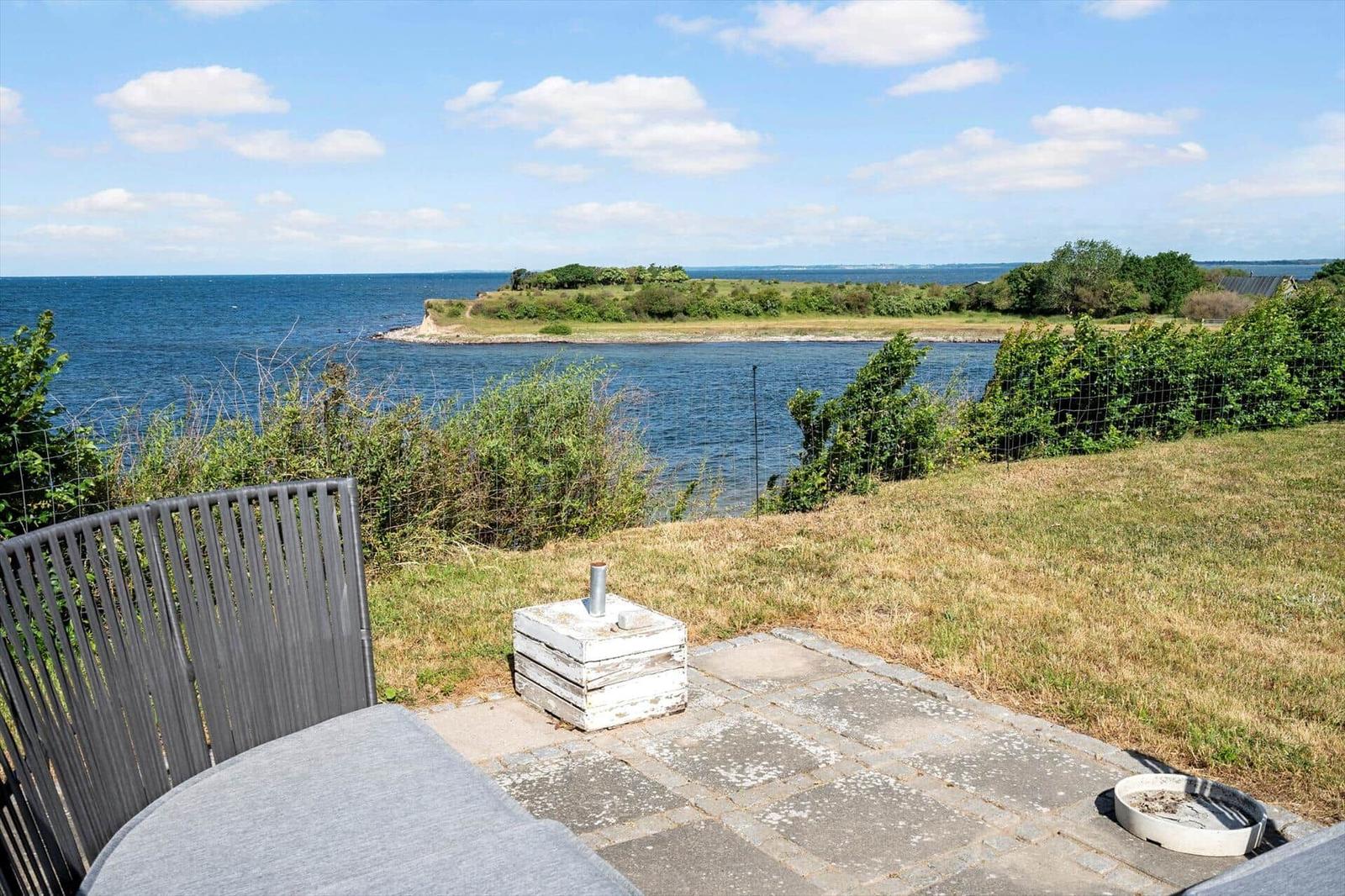 Terrace with seating and view of the sea and an island.