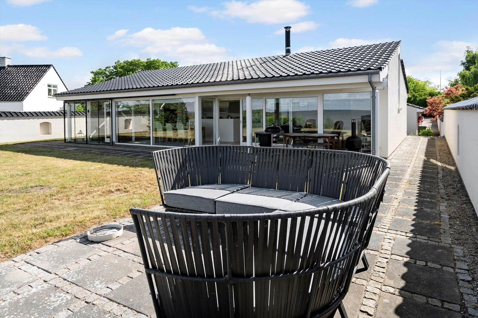Modern villa with large garden and terrace with rattan furniture.