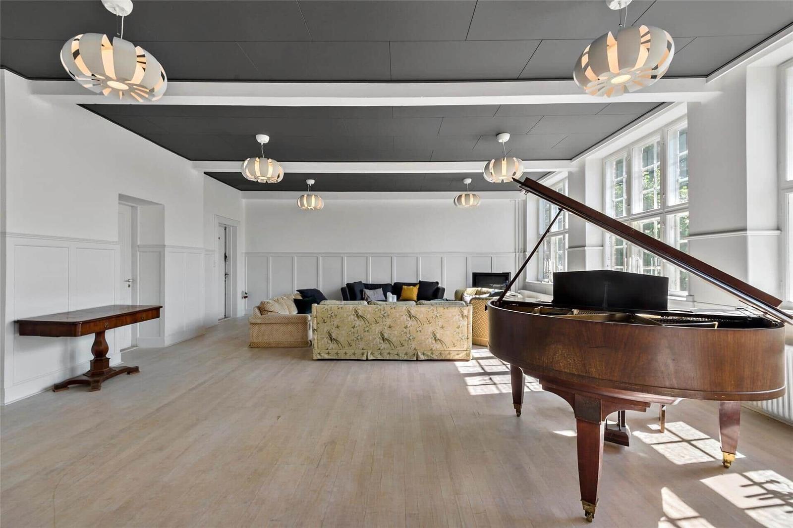 Großer Raum mit Flur, Sofa, Klavier und Deckenleuchten.