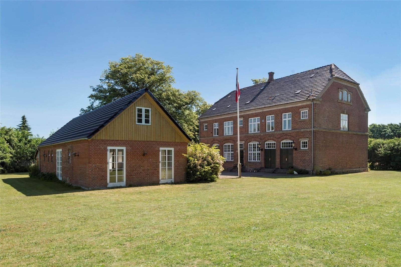 Zwei Gebäude aus Backstein mit grünem Rasen und Bäumen im Hintergrund.