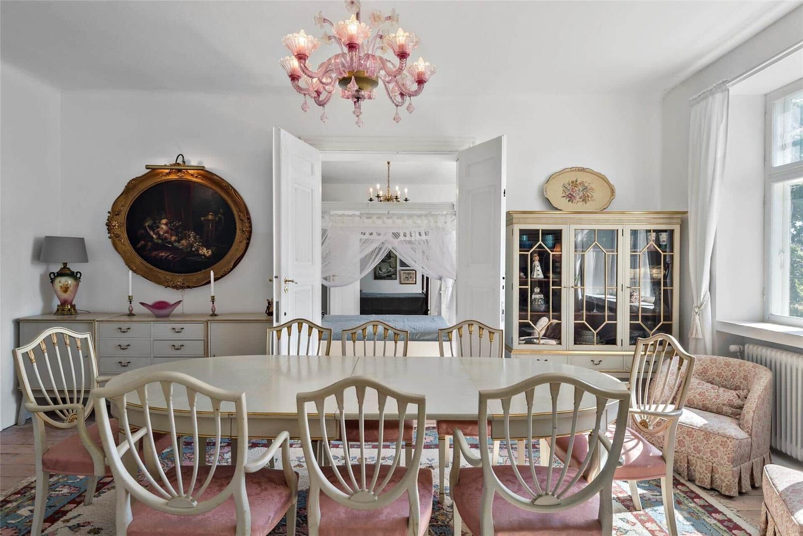 Esszimmer mit Tisch, Stühlen und Kronleuchter. Durchgang zur Schlafzimmer mit Baldachin.