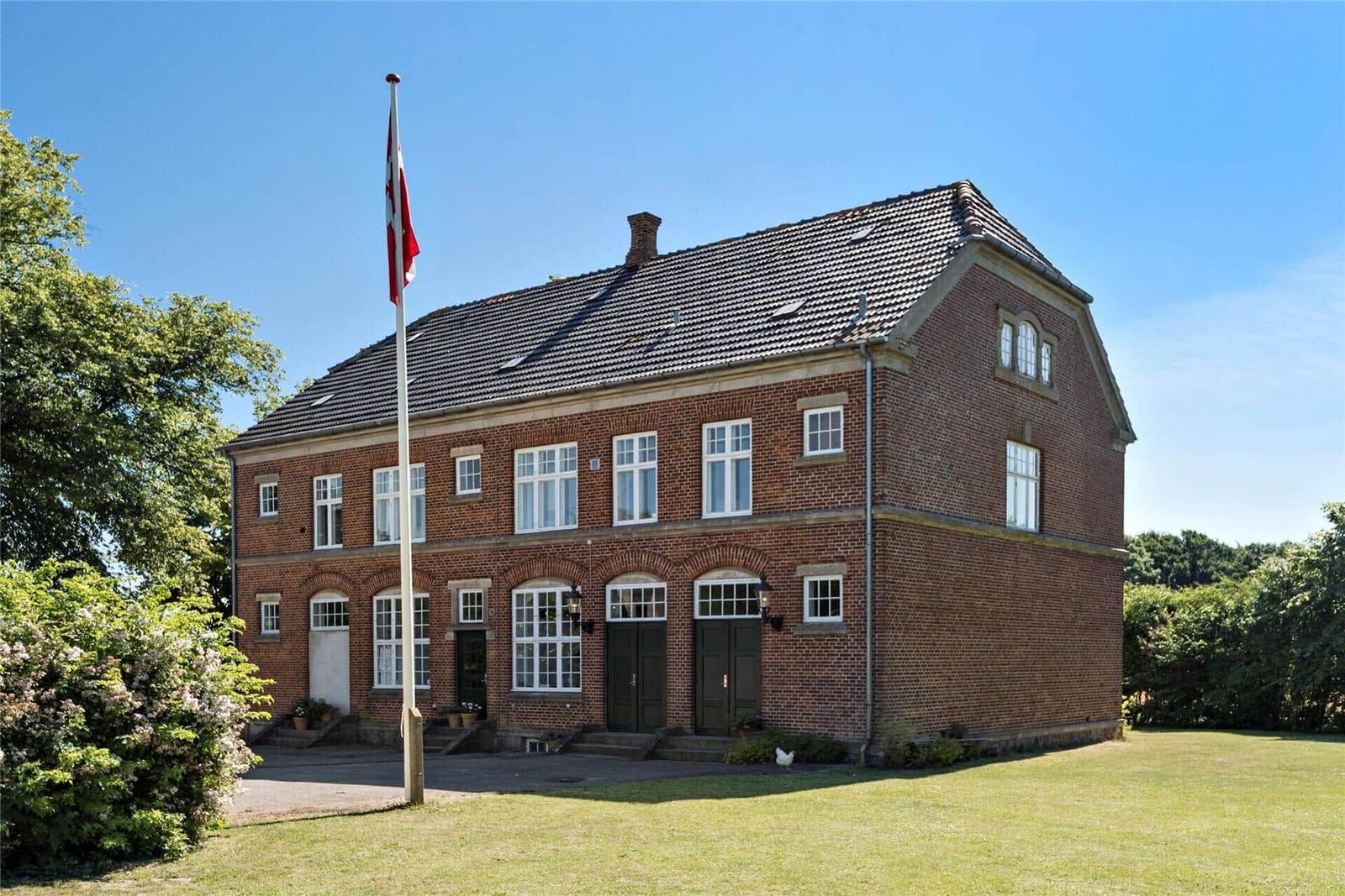 Zweistöckiges Backsteinhaus mit Flagge, Fenstern und Garten.