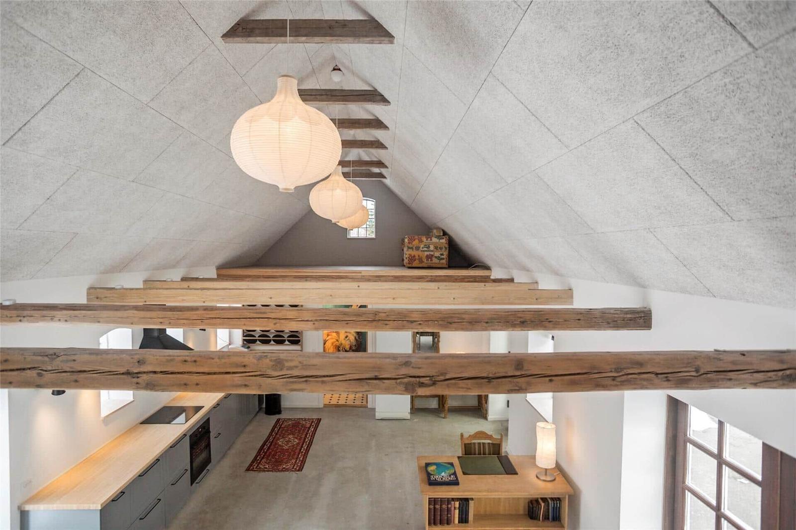 Haus mit Holzkonstruktion, Küchenbereich und Wohnfläche unter Dachschrägen.
