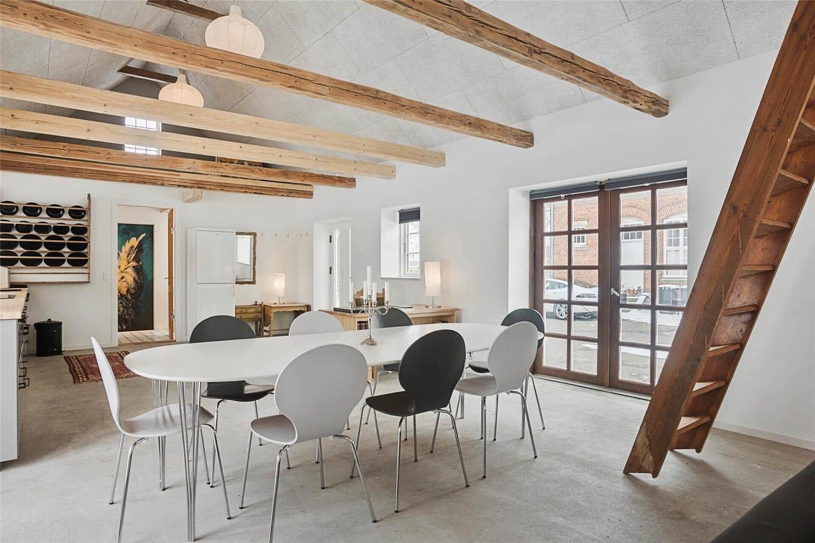 Esszimmer mit weißem Tisch, Stühlen und Holzbalken an der Decke.