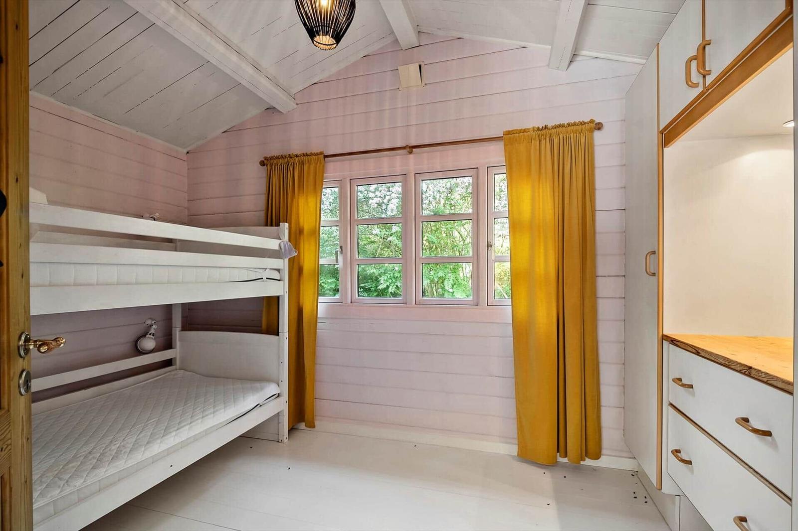 Zimmer mit Doppelstockbett, Fenster mit gelben Vorhängen und Schrank.