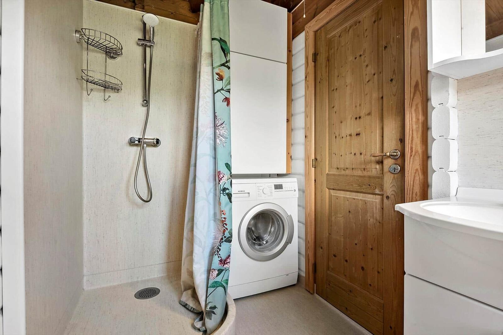 Dusche mit Duschbrause, Waschmaschine und Holztür