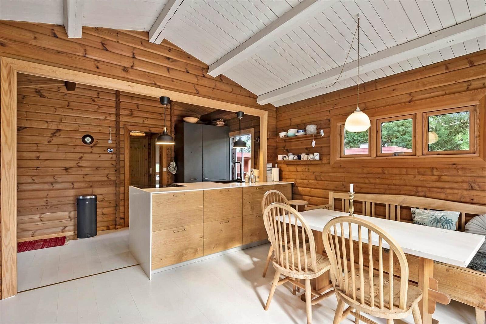 Küche und Essbereich mit Holzwand, weißem Boden und Holzmöbeln.