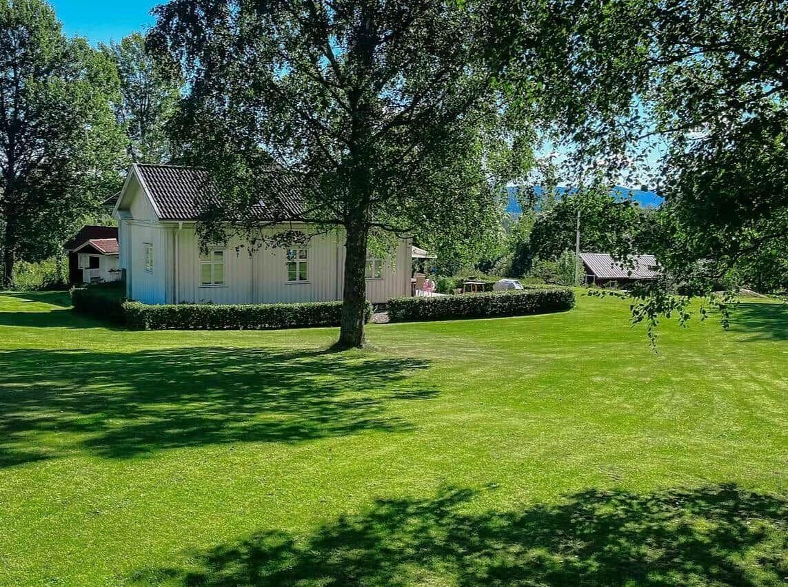 Ein weißes Haus mit grünem Rasen und Bäumen im Hintergrund.