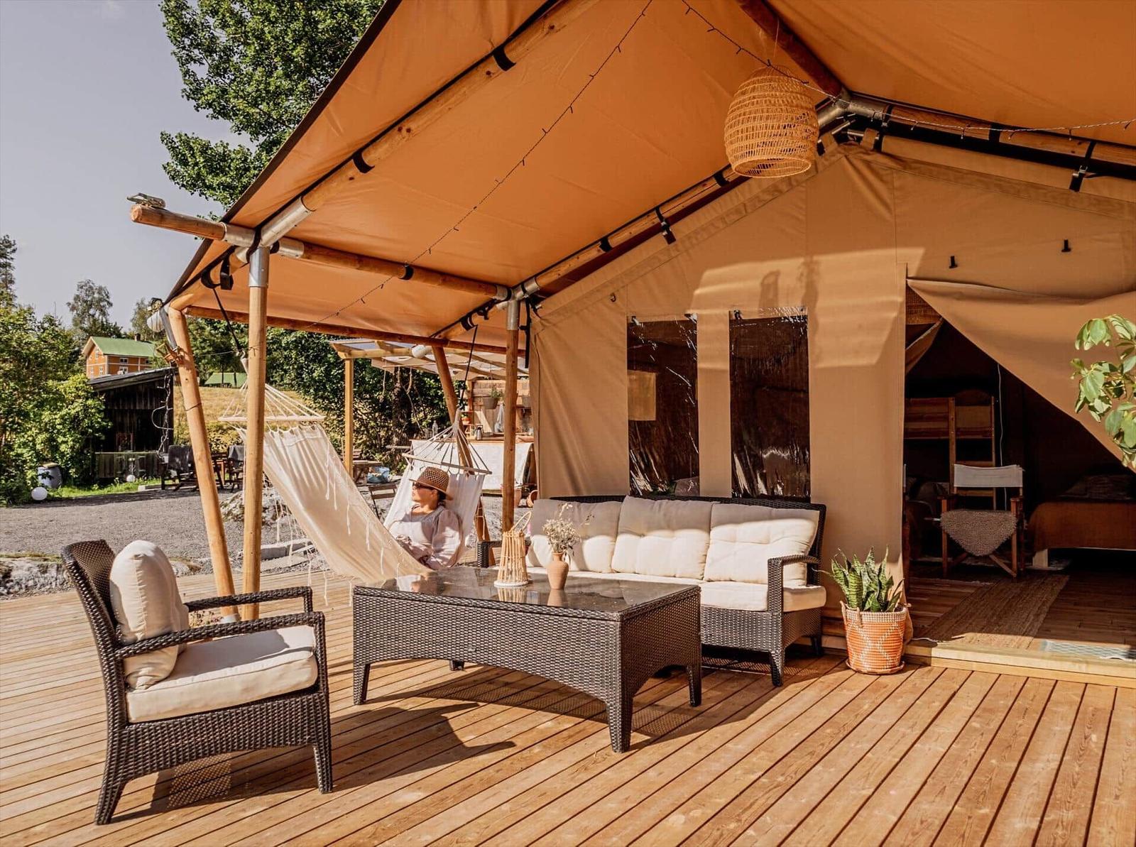 Terrasse mit Sitzgruppe, Hängematten und Blick in die Hütte.