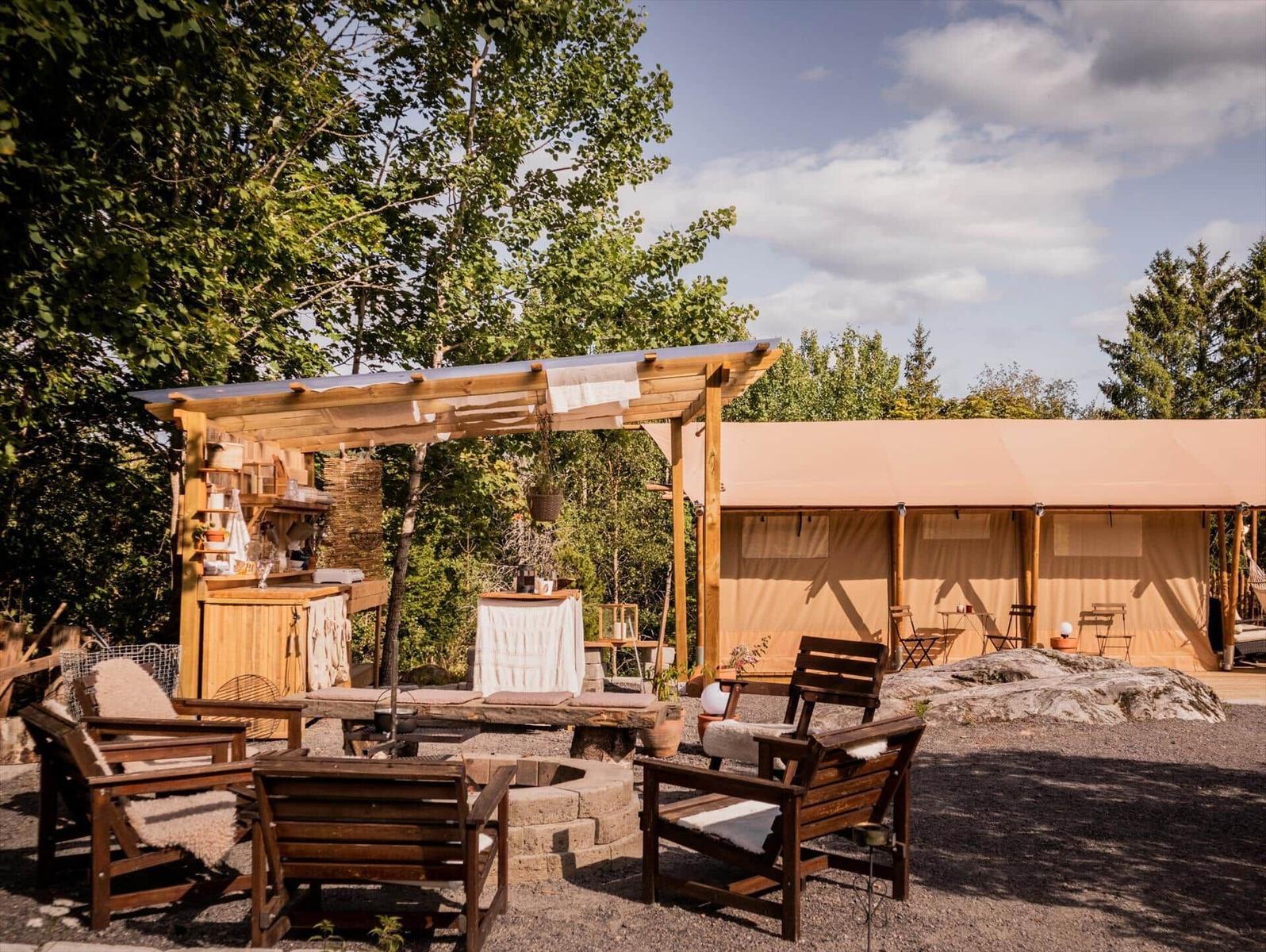 Außenbereich mit Loungebereich, Grillstation und Zeltunterkunft.