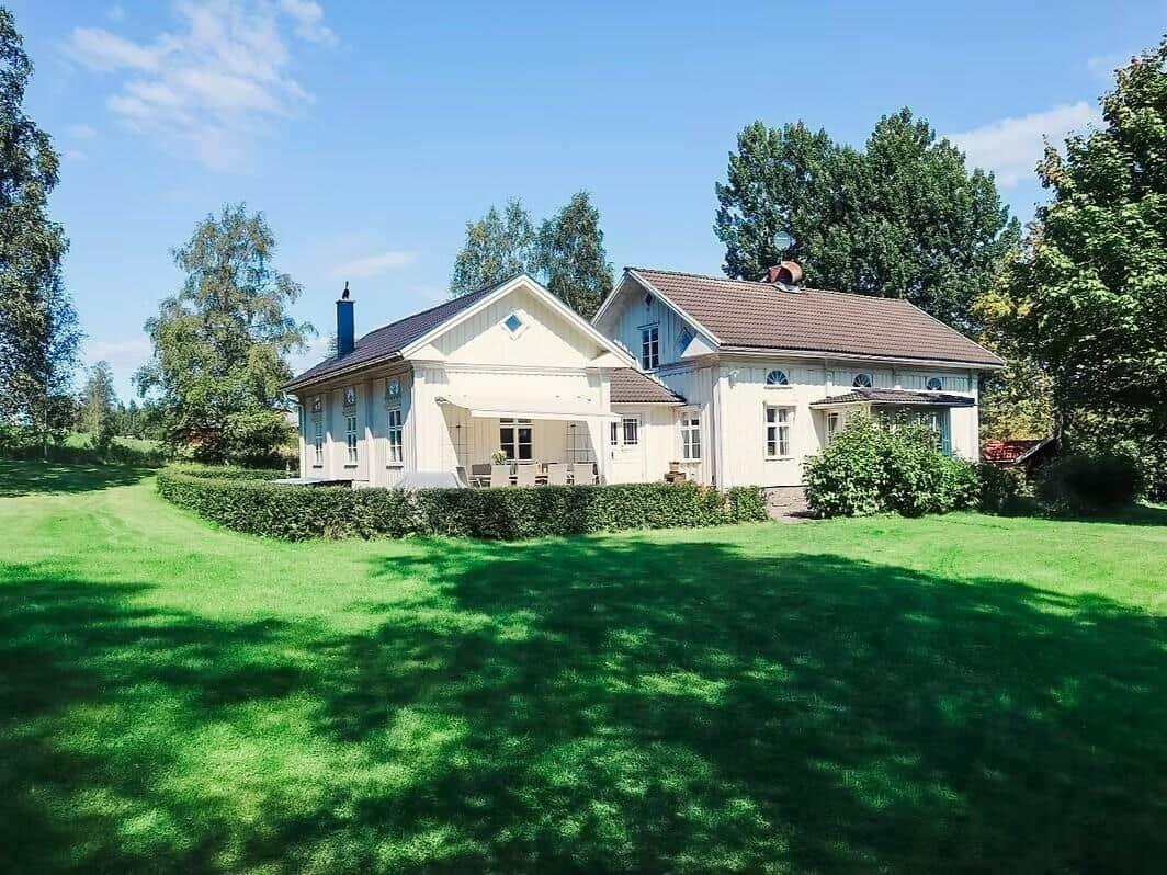 Haus mit großem Garten und Terrasse unter Bäumen.